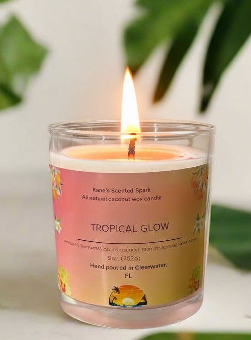 Tropical Glow coconut wax candle by Rene’s Scented Spark with a coral-colored wax top, in a glass jar with tropical floral label. Hand-poured in Clearwater, FL. Scented with mandarin, cassis, coconut, jasmine, sandalwood, and musk. Gift-ready tropical candle