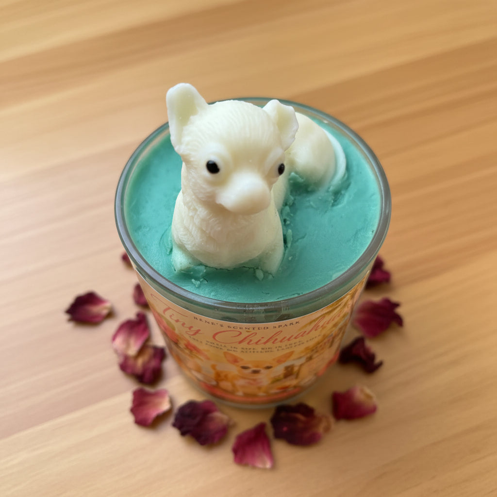 Candle with a Chihuahua-shaped mold on a wooden surface with dried flowe