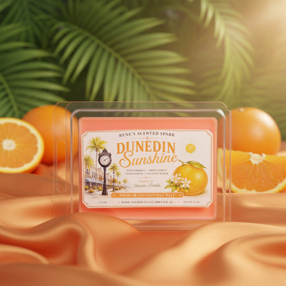Dunedin Sunshine orange citrus wax melts by Rene’s Scented Spark displayed with fresh oranges, tropical palm leaves, and flowing orange satin fabric.
