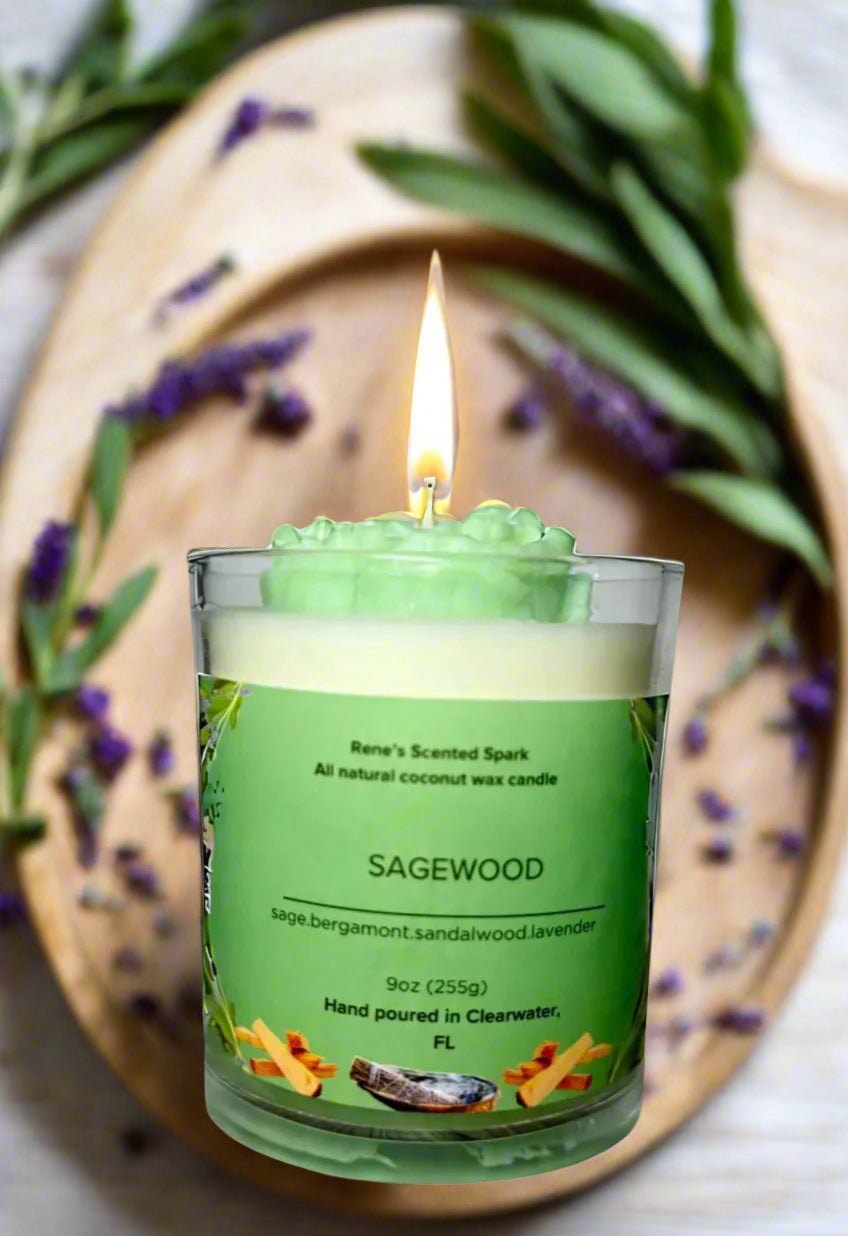 Sagewood candle glowing beside fresh sage leaves, lavender sprigs, and a wooden tray, creating a serene meditation space