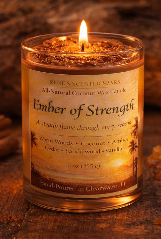 Candle labeled 'Ember of Strength' on a wooden surface with cinnamon sticks and amber pieces.