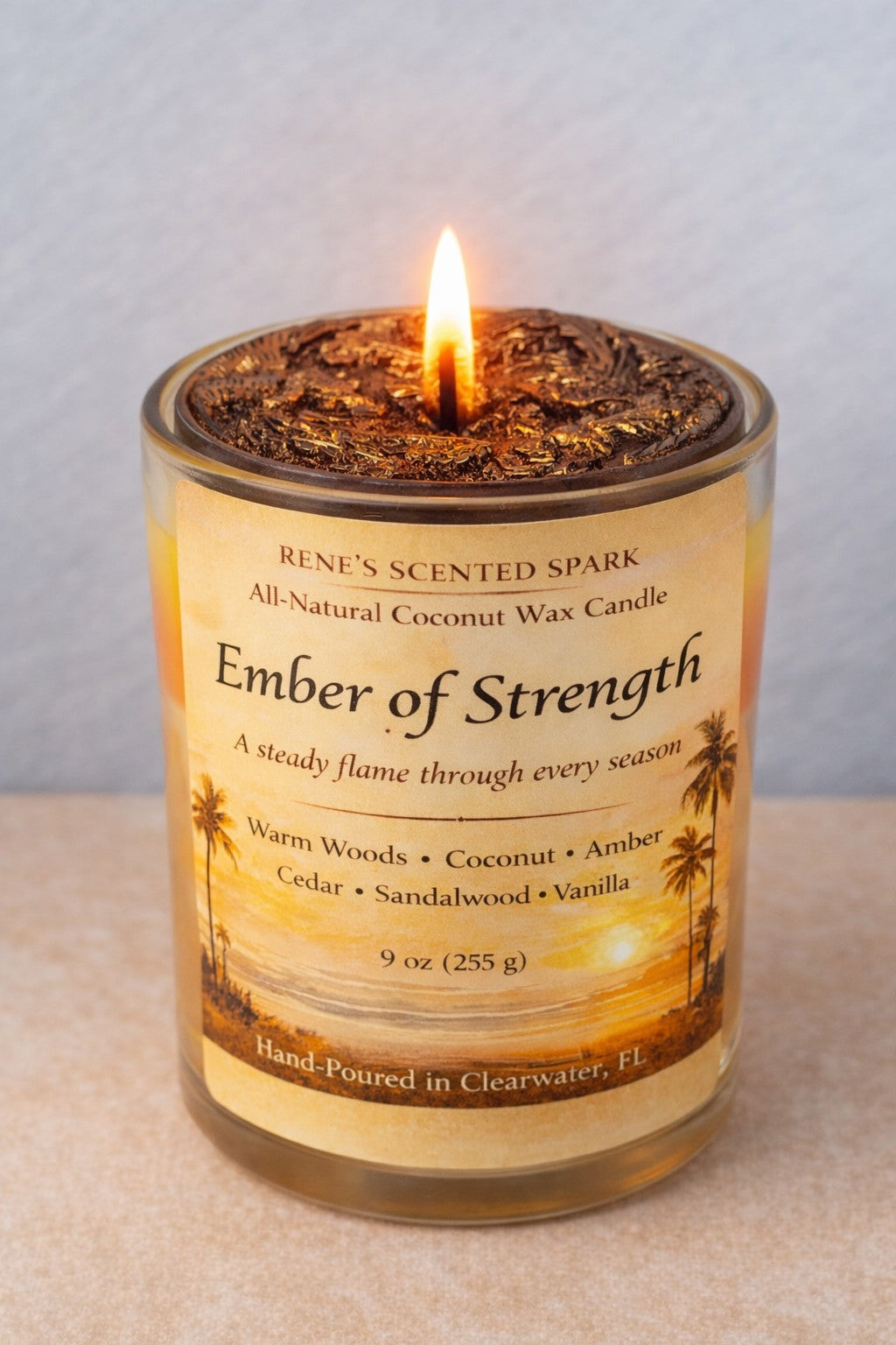 Hand-poured Ember of Strength coconut wax candle with warm golden sunset label and textured wax top, designed to symbolize resilience and hope