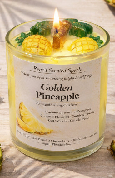 Lit Golden Pineapple candle on a beachy wood surface surrounded by fresh pineapple slices in warm tropical sunlight.