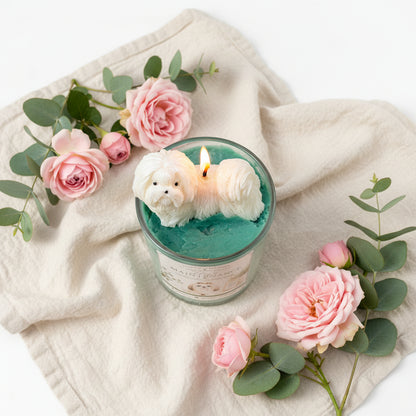 High Maintenance candle with white Shih Tzu topper surrounded by pink roses and cream blanket in cozy lifestyle setting
