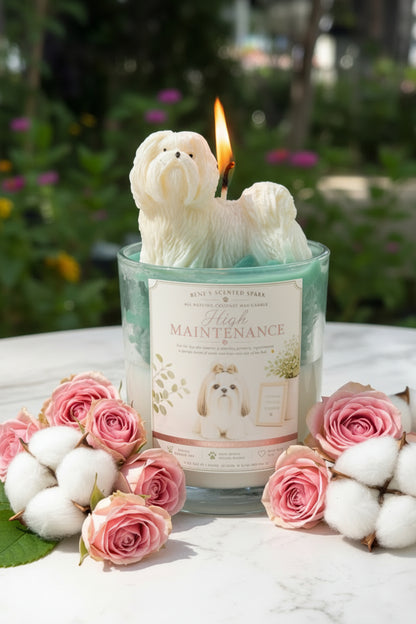 High Maintenance candle with white Shih Tzu topper surrounded by pink roses and cream blanket in cozy lifestyle setting