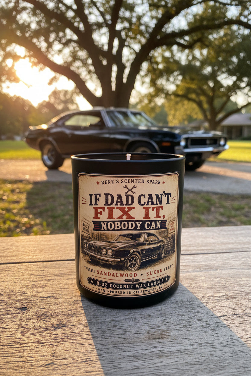 If Dad Can't Fix It Nobody Can sandalwood suede candle on a wooden surface at golden hour with a classic black muscle car in the background