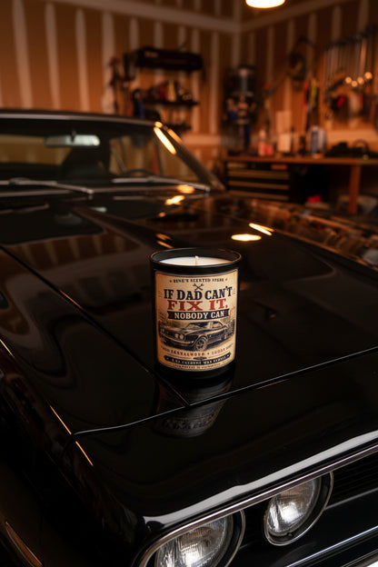If Dad Can't Fix It Nobody Can candle displayed in a dark moody garage setting with warm amber lighting
