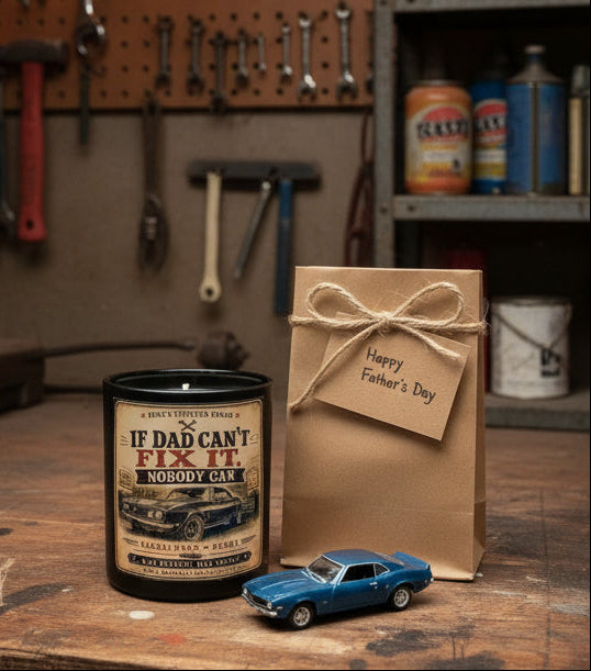 If Dad Can't Fix It Nobody Can Father's Day candle on a workbench with a toy classic car and gift wrapping nearby