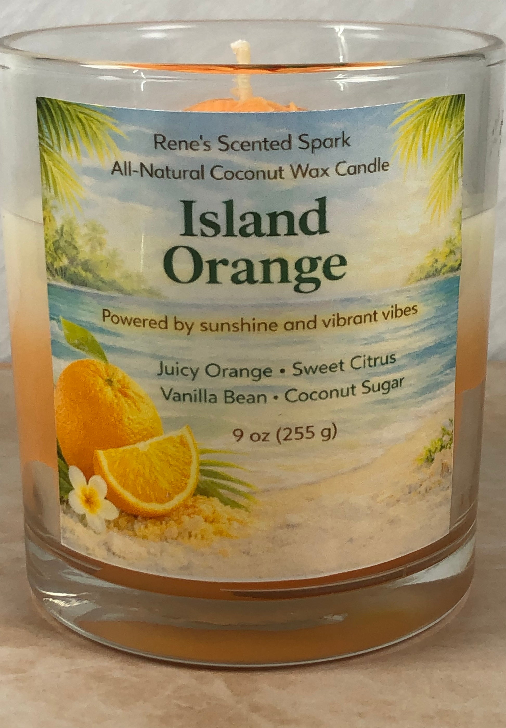 Candle labeled 'Island Orange' with a beach scene on the label