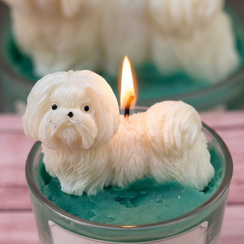 Little Royal dog candle with lit white flowing coat dog wax topper on teal green whipped wax on pink surface
