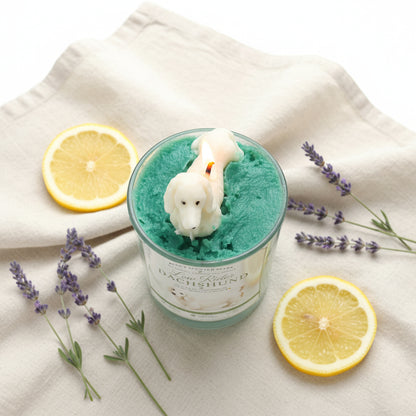 Low Rider Dachshund candle with cream dog topper on teal green wax with lemon slices and lavender on linen cloth