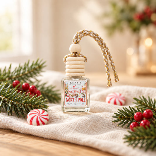North Pole peppermint and vanilla car freshener by Rene’s Scented Spark styled with peppermint candies, evergreen branches, pinecones, red berries, and warm Christmas lights