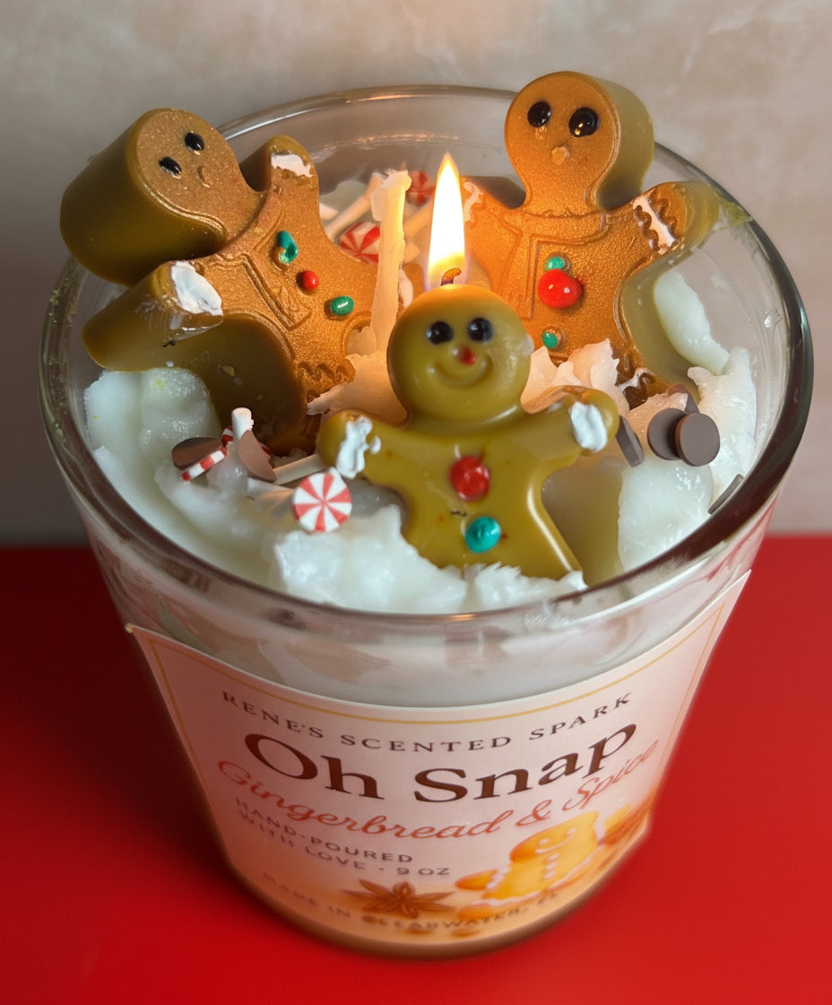 Candle in a glass jar with gingerbread-themed decorations on a red surface