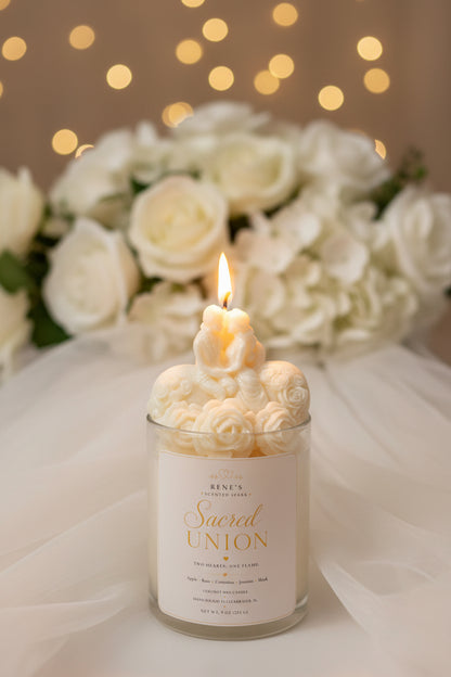 Sacred Union romantic wedding candle with bride and groom topper, white roses, and warm glowing lights