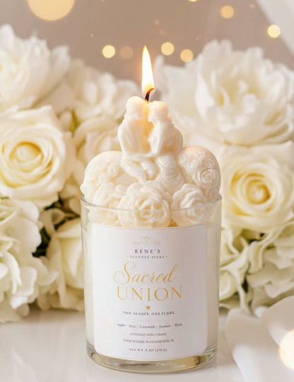 Bride and groom candle in glass jar with sculpted roses, glowing flame, white roses, and soft warm lights in background