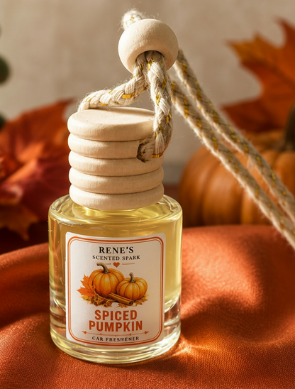 Close-up of Spiced Pumpkin hanging car freshener by Renes Scented Spark with wooden diffuser cap, styled with pumpkins and autumn leaves.