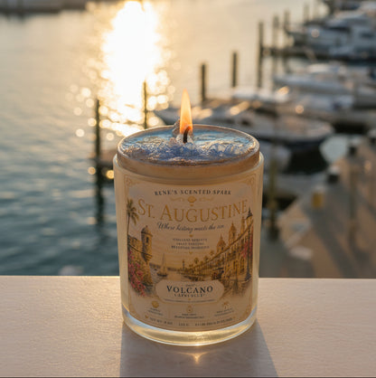 Lit St. Augustine coconut wax candle by Rene's Scented Spark displayed overlooking a marina at sunset, featuring a vintage Florida-inspired label and hand-poured glass jar.