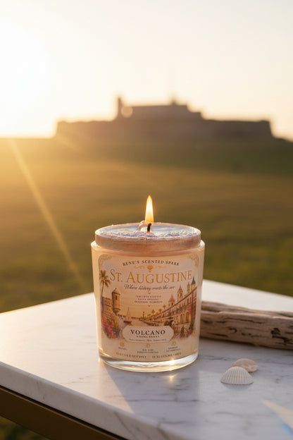 Lit St. Augustine coconut wax candle by Rene's Scented Spark displayed outdoors at sunset with Castillo de San Marcos in the background and a vintage-inspired Florida label.