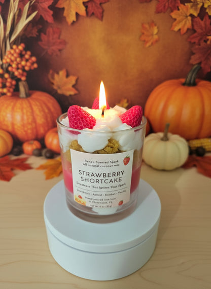 Strawberry shortcake candle with raspberries on top, surrounded by pumpkins and autumn leaves.