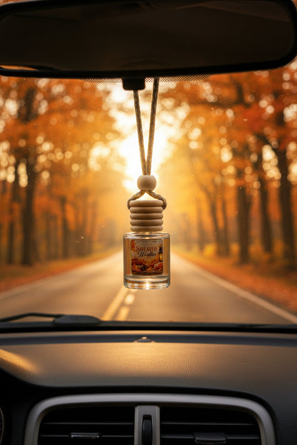 Sweater Weather hanging car freshener by Rene’s Scented Spark displayed from a rearview mirror on a scenic autumn road surrounded by glowing orange and golden fall trees