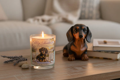 Candle with a dog-themed label next to a small dog figurine on a table.