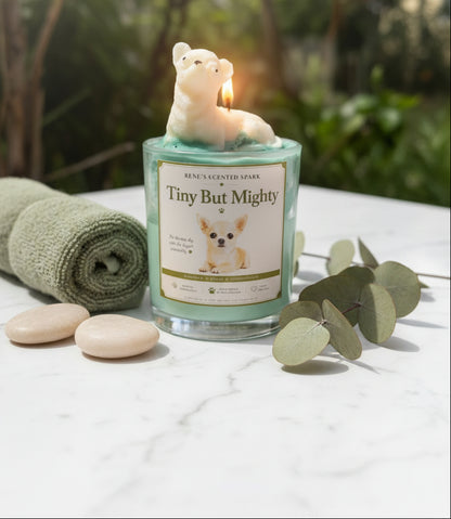 Tiny But Mighty Chihuahua candle on white bathroom shelf with cream towels and small green tropical plant