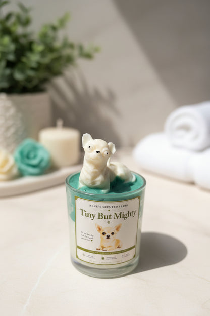 Candle with a dog-shaped candle wick holder on a decorative surface with flowers and leaves.