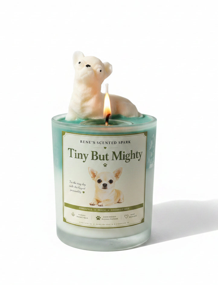 Tiny But Mighty candle with lit cream Chihuahua wax topper on teal green wax with Tiny But Mighty sign on marble