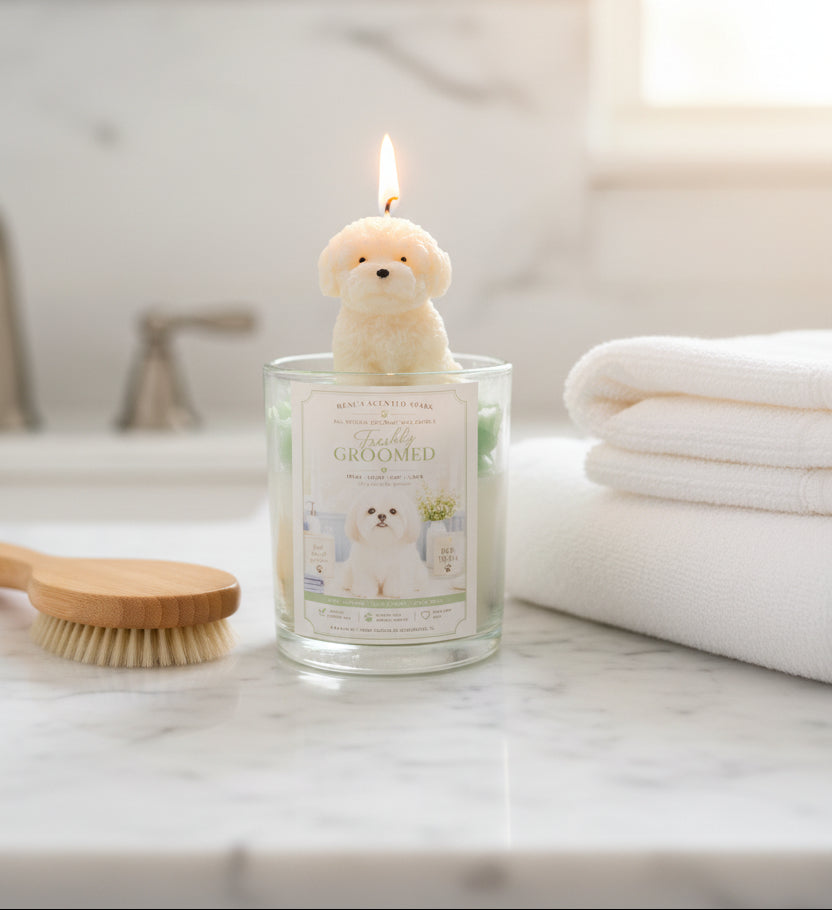 Candle with a dog-shaped wick on a marble surface with towels and a brush in the background