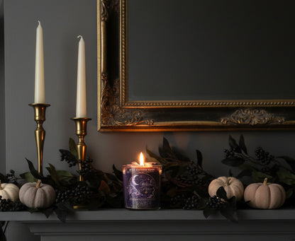 Witches Brew Halloween coconut wax candle glowing on an elegant dark mantel with white pumpkins, black greenery, and vintage brass candlesticks.