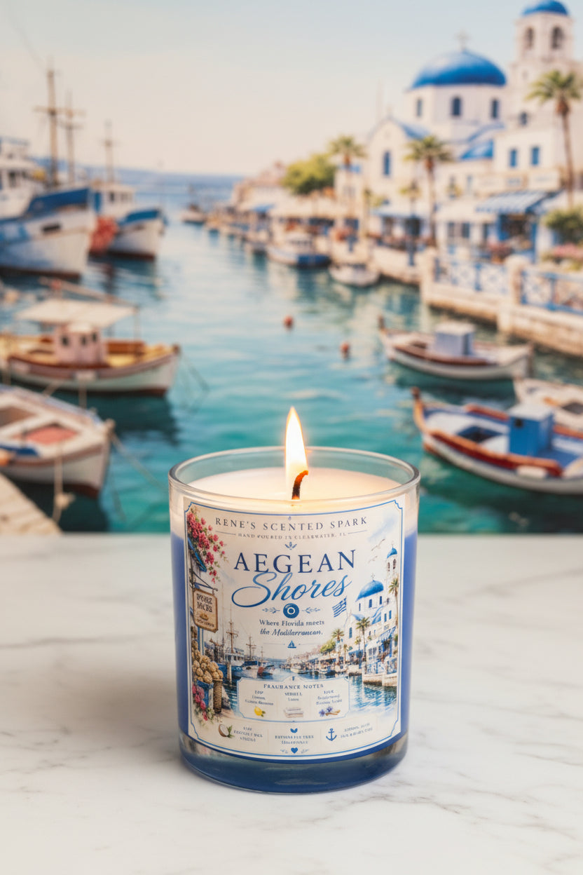 Lit Aegean Shores coconut wax candle by Rene's Scented Spark displayed before a picturesque Mediterranean-style harbor with blue-domed buildings, boats, and crystal blue water.