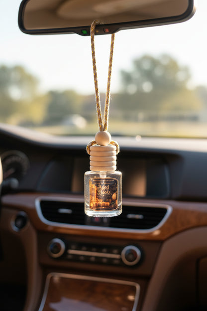 Aged Books car freshener by Renes Scented Spark hanging from a car rearview mirror, featuring a wooden diffuser cap and vintage book-inspired label.