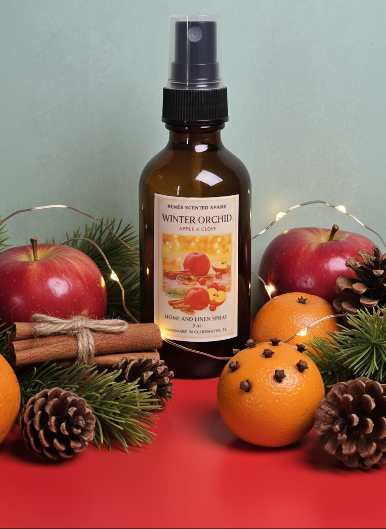 Bottle of 'Winter Orchid' home and linen spray surrounded by apples, oranges, and pinecones on a red surface.