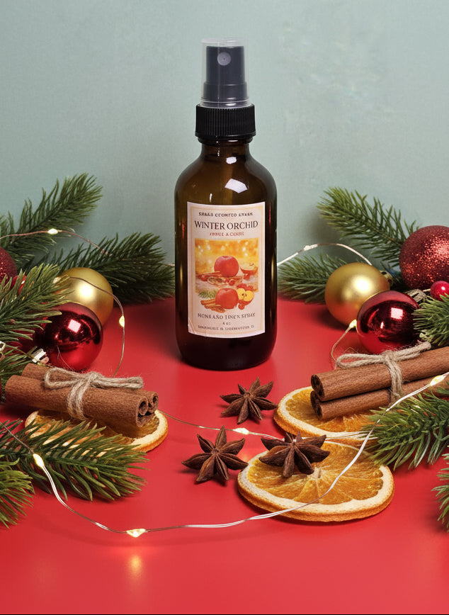 Bottle of 'Winter Orchard' spray with Christmas decorations on a red surface