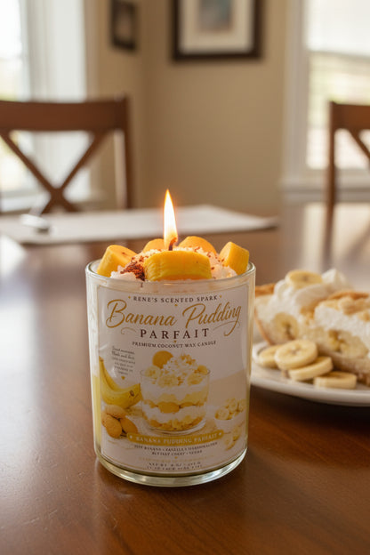 Banana pudding scented candle in a glass jar on a wooden table with a plate of banana pudding in the background.