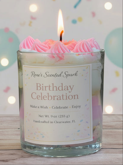 Candle in a glass jar labeled 'Birthday Celebration' with pink frosting on top, against a light background.