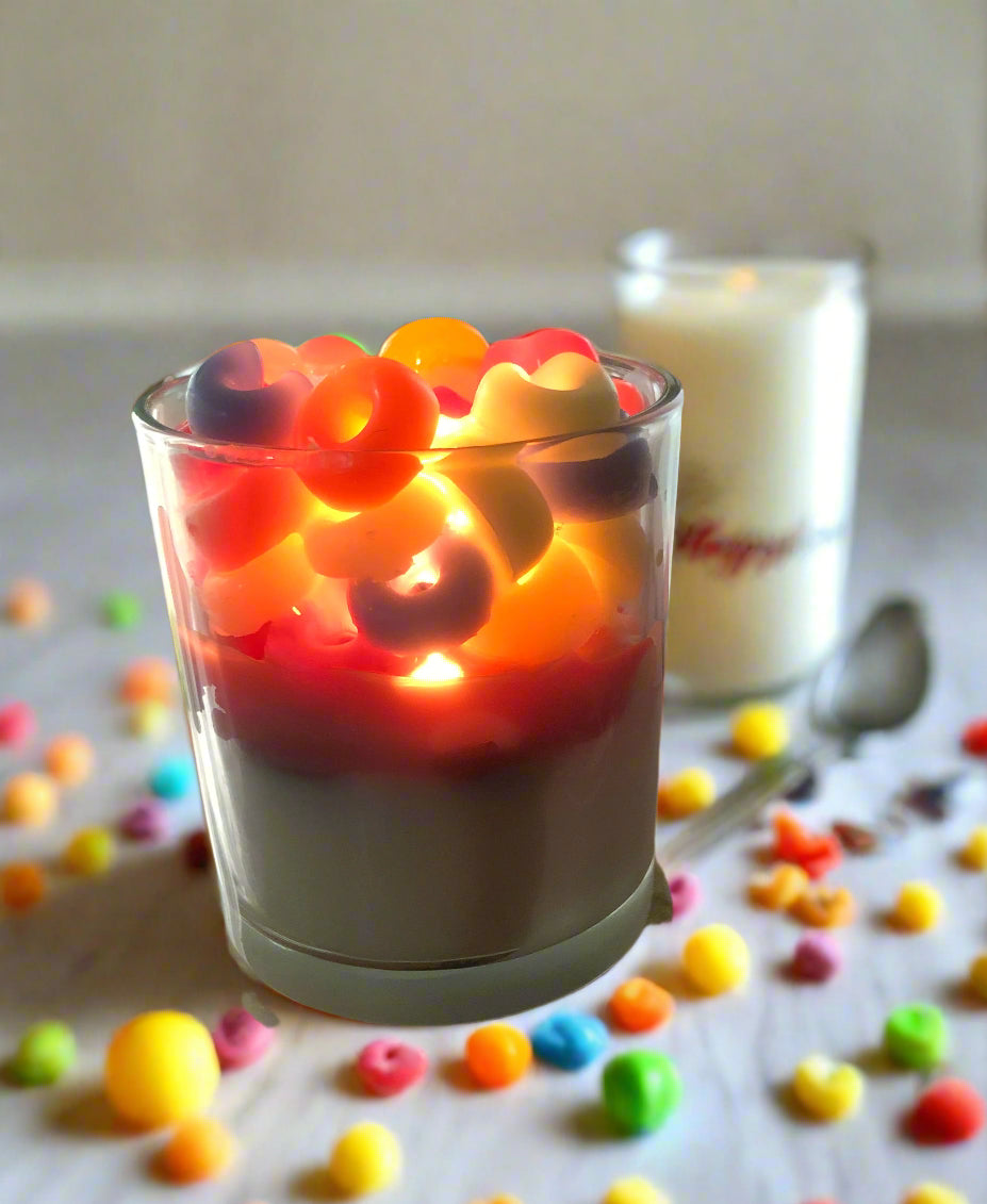 Morning Mischief fruity cereal candle glowing beside a colorful cereal bowl, spoon, and milk
