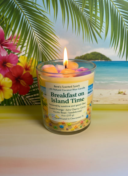 Breakfast on Island Time coconut wax candle with tropical label, lit wick, and colorful fruit-inspired details against a palm leaf background.