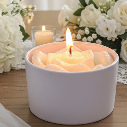 4 oz wedding favor candle with sculpted white rose wax topper, lit and displayed among elegant white wedding flowers.