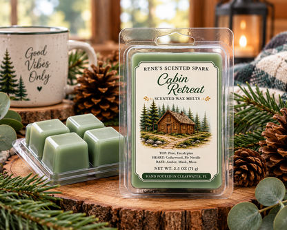 Cabin Retreat scented wax melts by Renes Scented Spark styled with green wax cubes, pinecones, evergreen branches and a cozy mug in a warm rustic cabin setting.