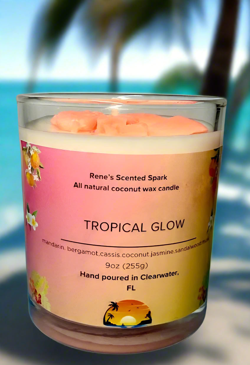 Tropical Glow coconut wax candle by Rene’s Scented Spark with a coral-colored wax top, in a glass jar with tropical floral label. Hand-poured in Clearwater, FL. Scented with mandarin, cassis, coconut, jasmine, sandalwood, and musk. Gift-ready tropical candle