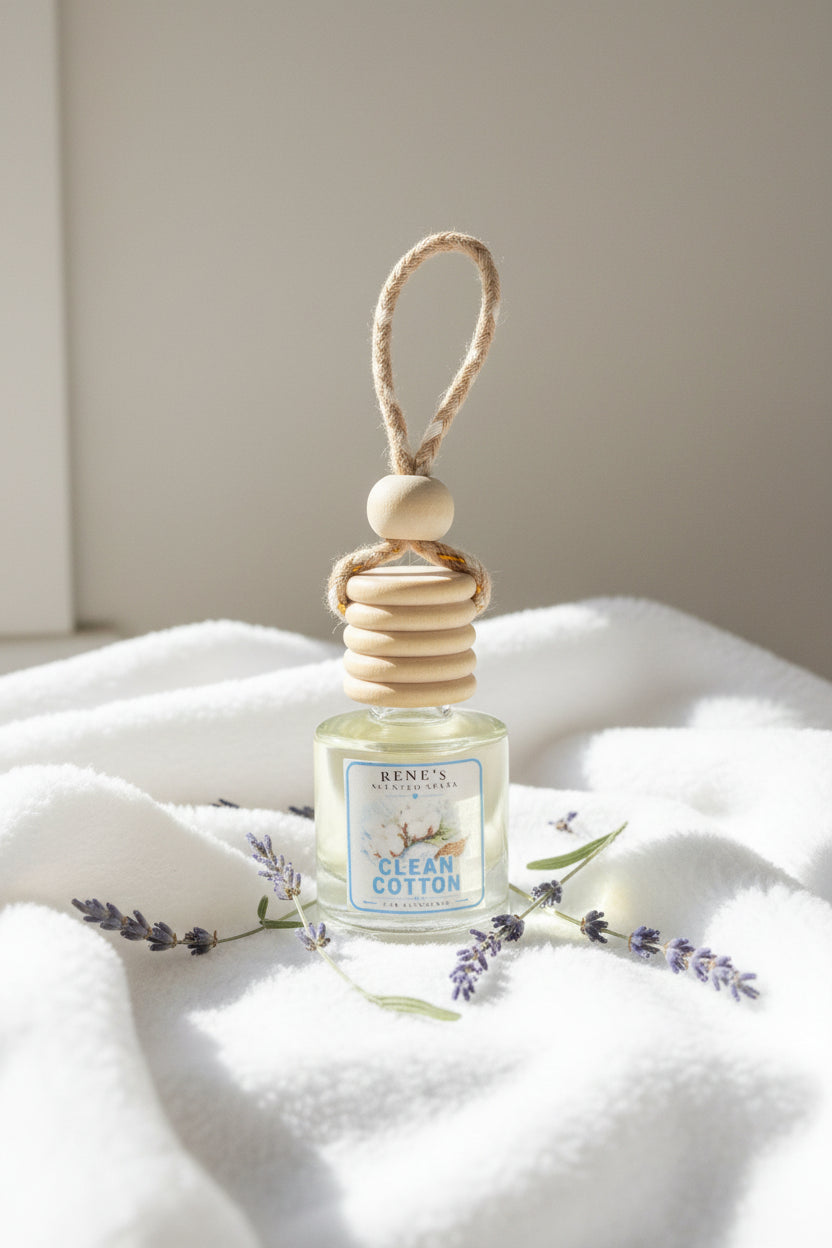 Clean Cotton hanging car air freshener by Rene’s Scented Spark displayed on soft white fabric with delicate lavender sprigs and greenery in a bright, clean setting.