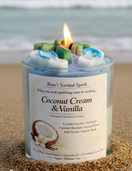 Candle labeled 'Coconut Cream & Vanilla' on a sandy surface with a beach background