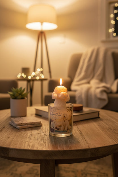 Dog lover coconut wax candle featuring a white poodle-shaped wax topper and Elegant Soul label, styled on a wooden coffee table in a warm, cozy living room with soft lighting, books, and home décor.