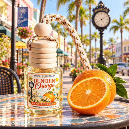 Dunedin Orange car air freshener on a café table on a sunny Florida main street with palm trees and a vintage clock