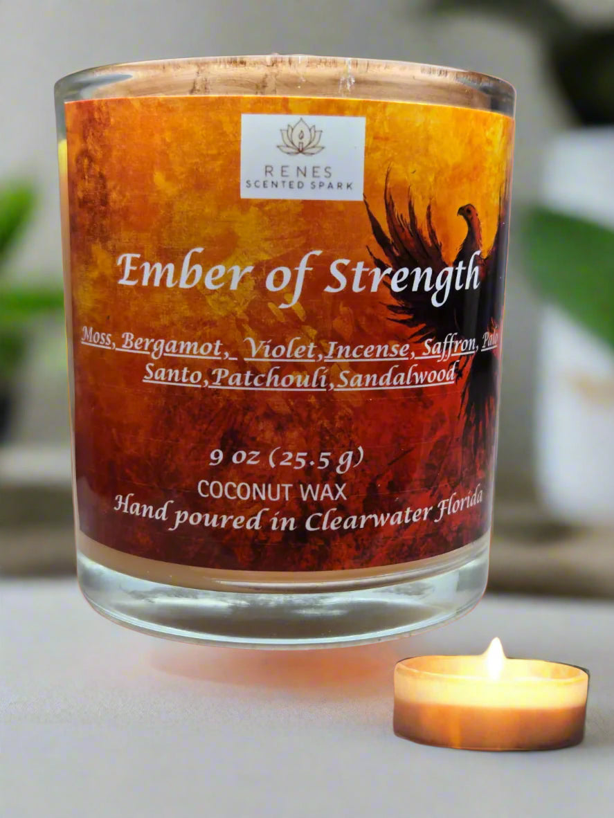 Spiritual candle collection displayed on a wooden table with Ember of Strength candle topped with phoenix and dragon, and Tranquil Spirit candle beside a Buddha figure. Surrounded by crystals, stones, and greenery — symbolic gift candles for meditation, healing, and renewal