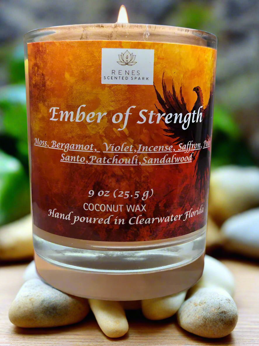 Spiritual candle collection displayed on a wooden table with Ember of Strength candle topped with phoenix and dragon, and Tranquil Spirit candle beside a Buddha figure. Surrounded by crystals, stones, and greenery — symbolic gift candles for meditation, healing, and renewal