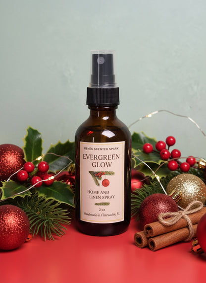 Amber glass bottle labeled “Evergreen Glow Home & Linen Spray” by René’s Scented Spark, displayed in front of a glowing Christmas decoration