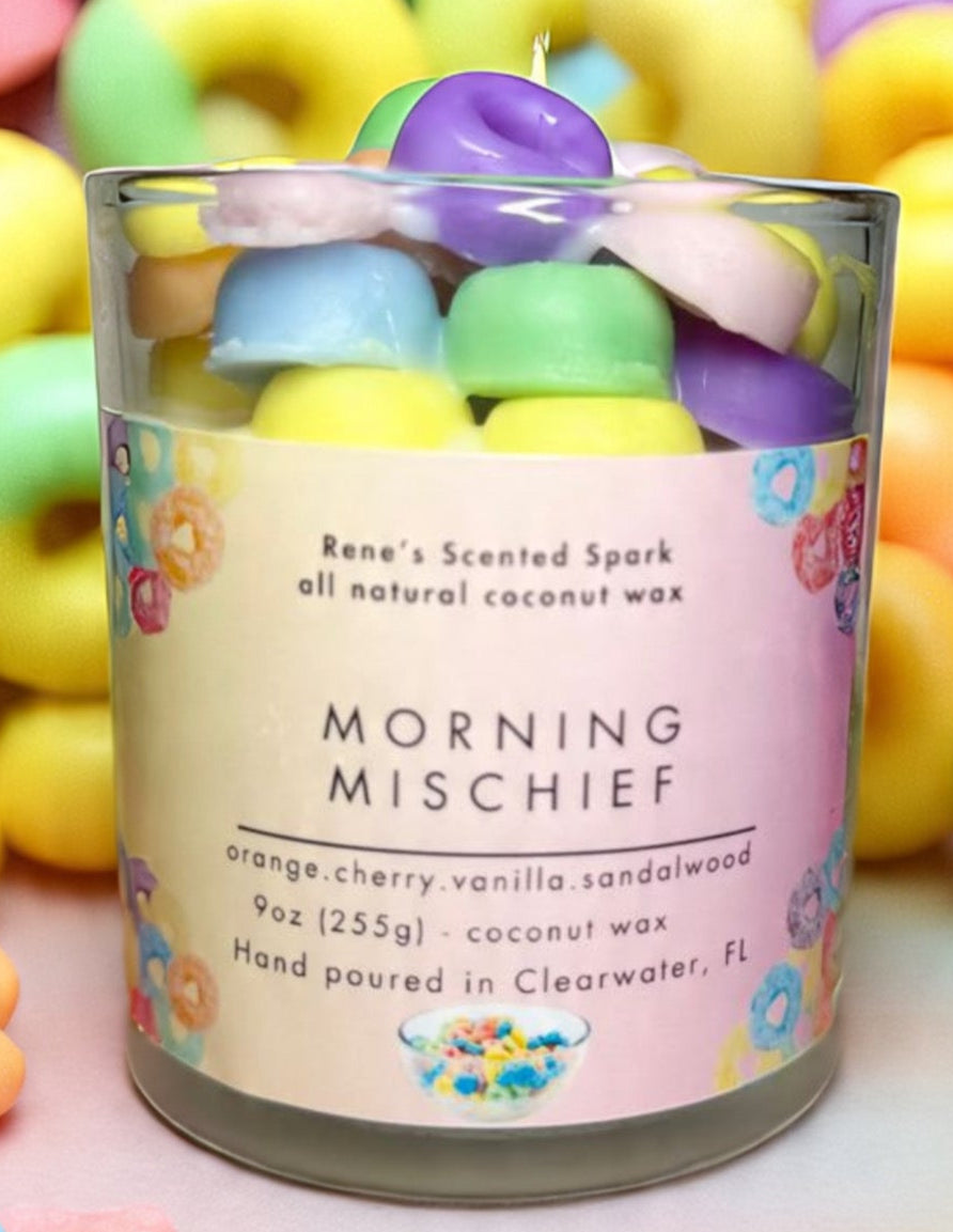 Morning Mischief fruity cereal candle glowing beside a colorful cereal bowl, spoon, and milk
