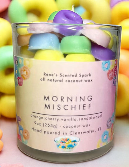 Morning Mischief fruity cereal candle glowing beside a colorful cereal bowl, spoon, and milk